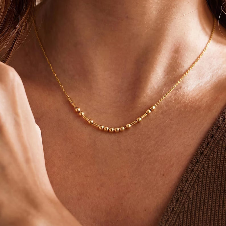 Detalhe das contas do Colar Código Morse dourado no colo