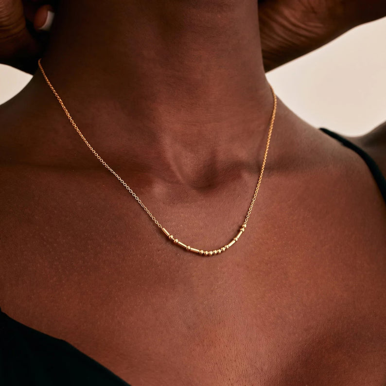 Mulher negra usando o Colar Código Morse dourado